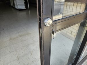 Commercial locksmith installing a high-security mortise lock on a business storefront door.